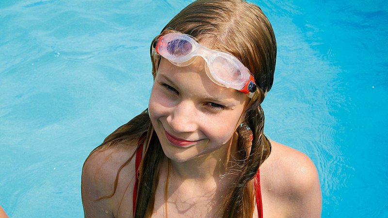 Mädchen im Schwimmbad mit Taucherbrille auf der Sitrn