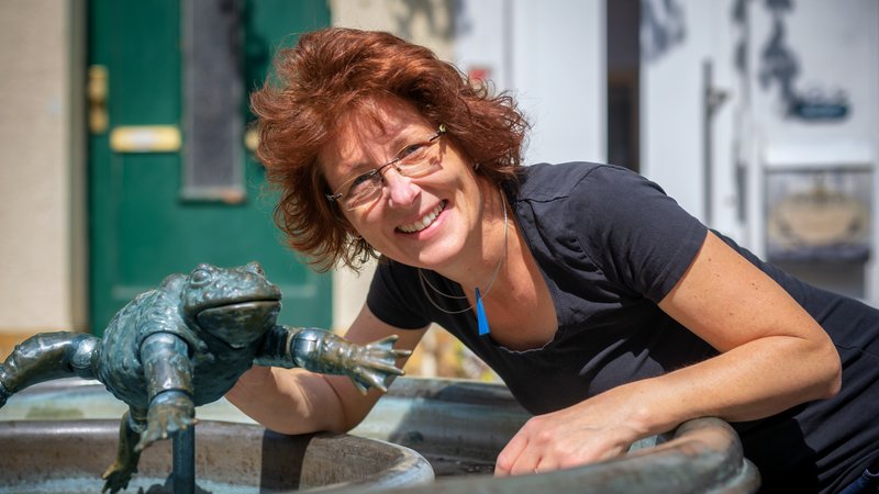 Portrait: Autorin/Illustratorin Anke Faust am Brunnen mit Froschfigur