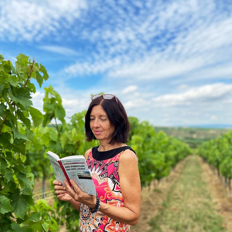 Portrait von Angelika Angermeier vor grünem Weinlaub unter blauem Himmel