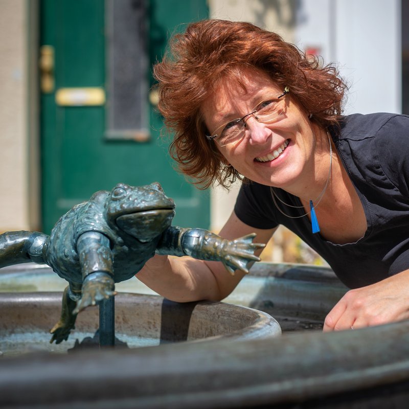 Portrait: Autorin/Illustratorin Anke Faust am Brunnen mit Froschfigur