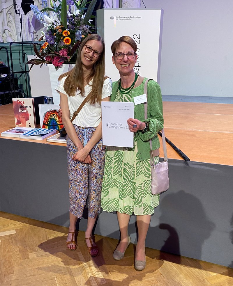 Verlegerin Annette Sievers mit der Urkunde und Azubi Marie Mühling freuen sich über die Auszeichnung